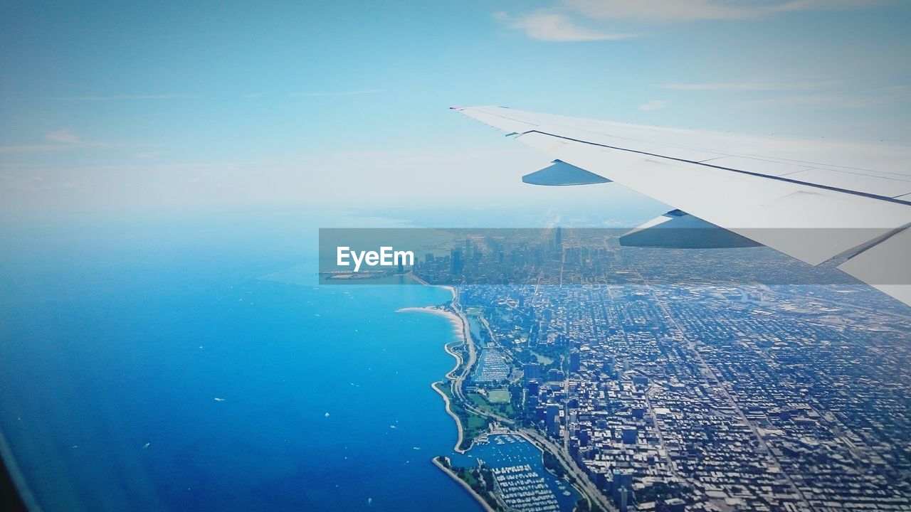 CROPPED IMAGE OF AIRPLANE FLYING OVER SEA AGAINST SKY