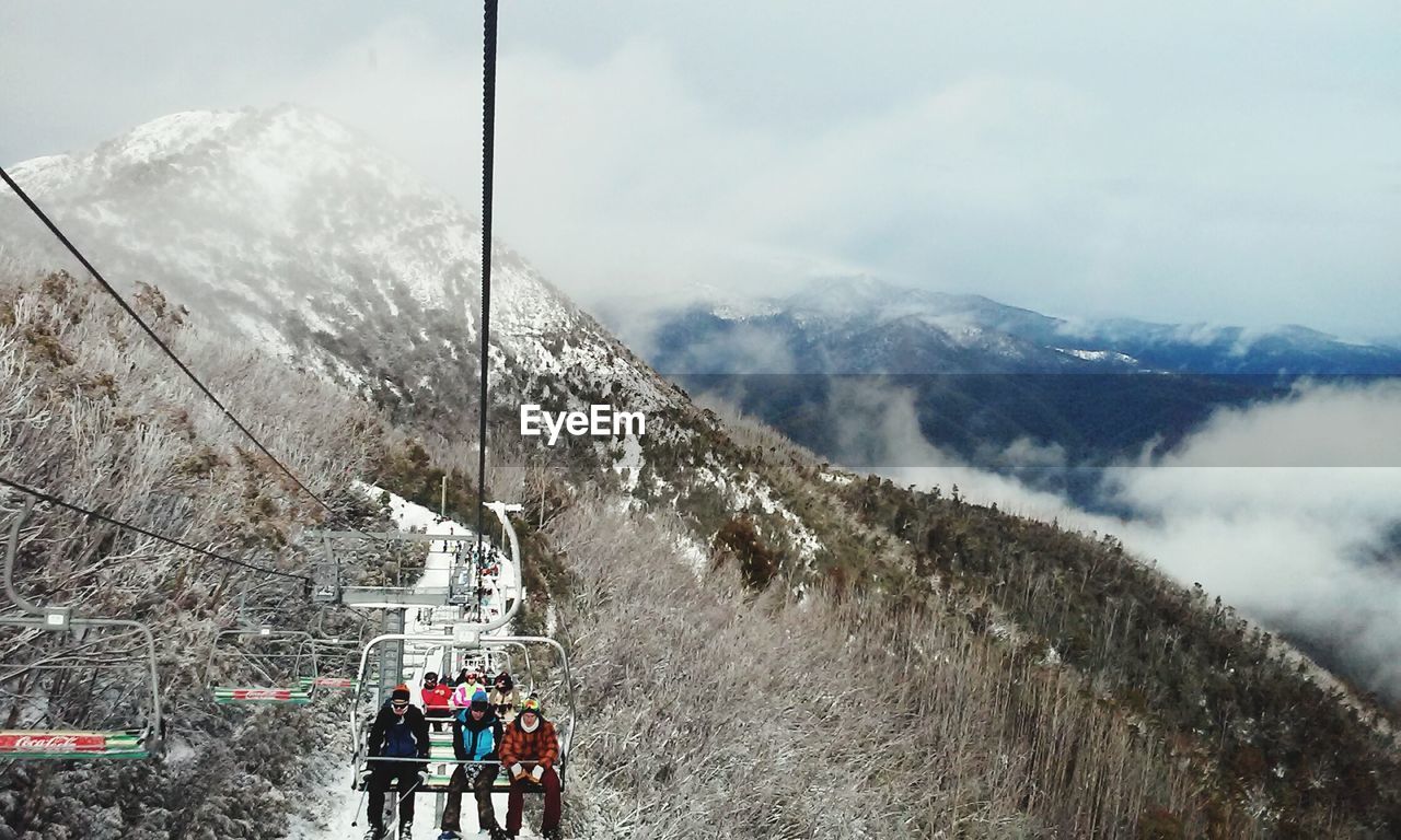 People at overhead cable car against mountains