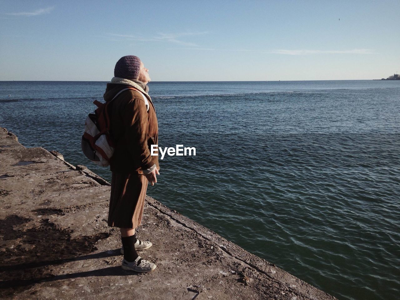 Woman standing on pier by sea against sky