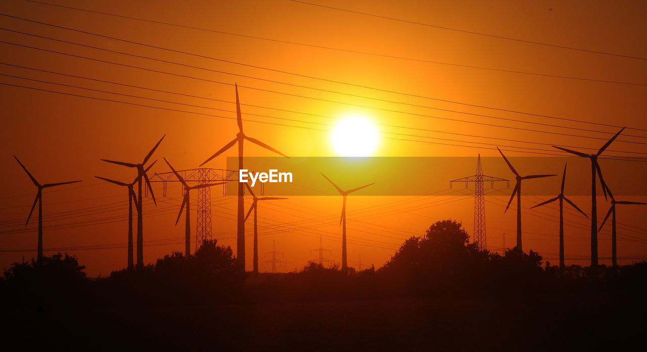 SILHOUETTE ELECTRICITY PYLONS AGAINST ORANGE SKY