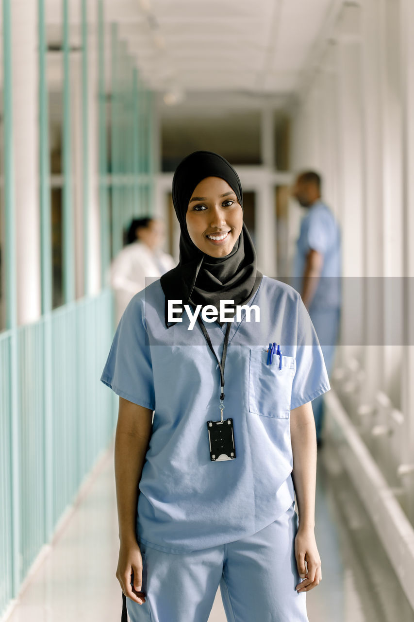 Portrait of smiling female nurse standing in hospital corridor