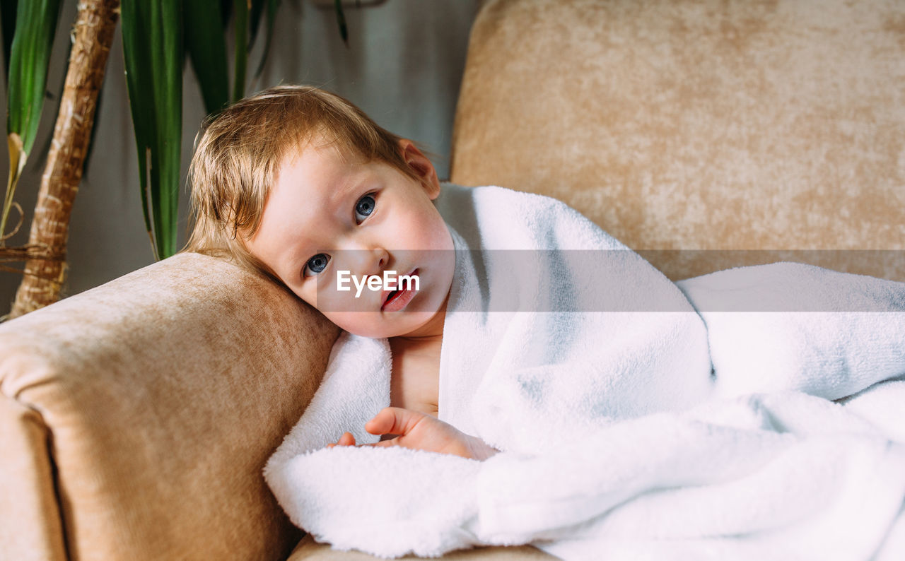 Cute child with blue eyes wrapped in a white towel.