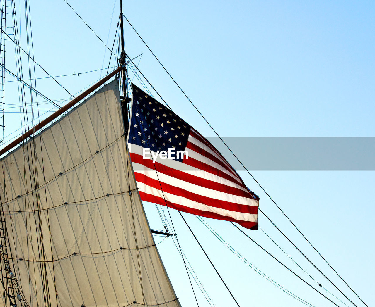 Low angle view of american flag on mast against clear blue sky