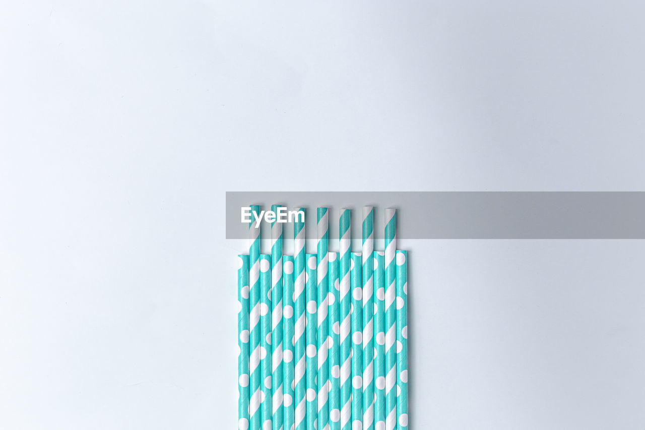 Close-up of drinking straws against white background