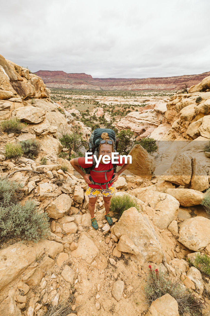 Female hiker with hands on hips looks at camera while hiking utah