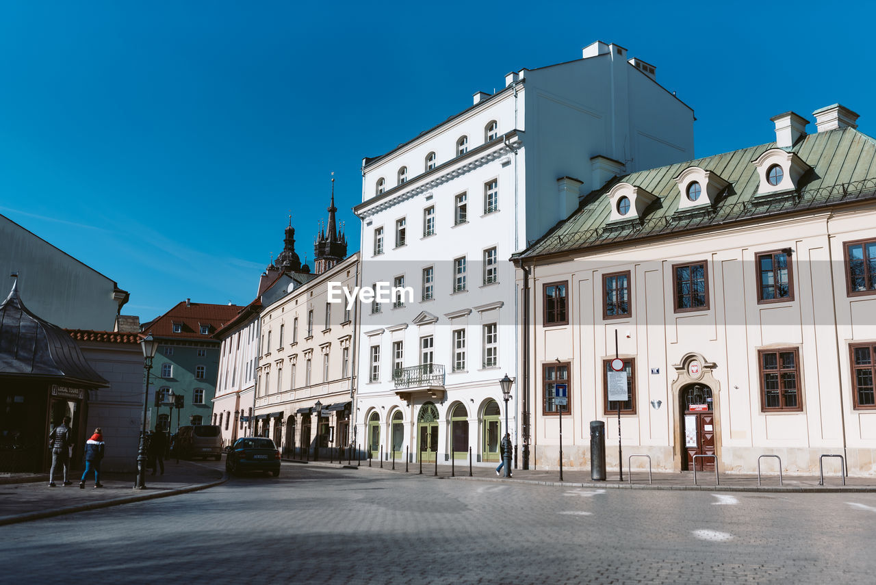 architecture, building exterior, built structure, town, city, street, sky, building, neighbourhood, urban area, cityscape, downtown, clear sky, road, nature, travel destinations, blue, landmark, facade, city street, town square, residential district, sunny, transportation, the past, no people, history, residential area, outdoors, travel, house, window, day, tourism, city life