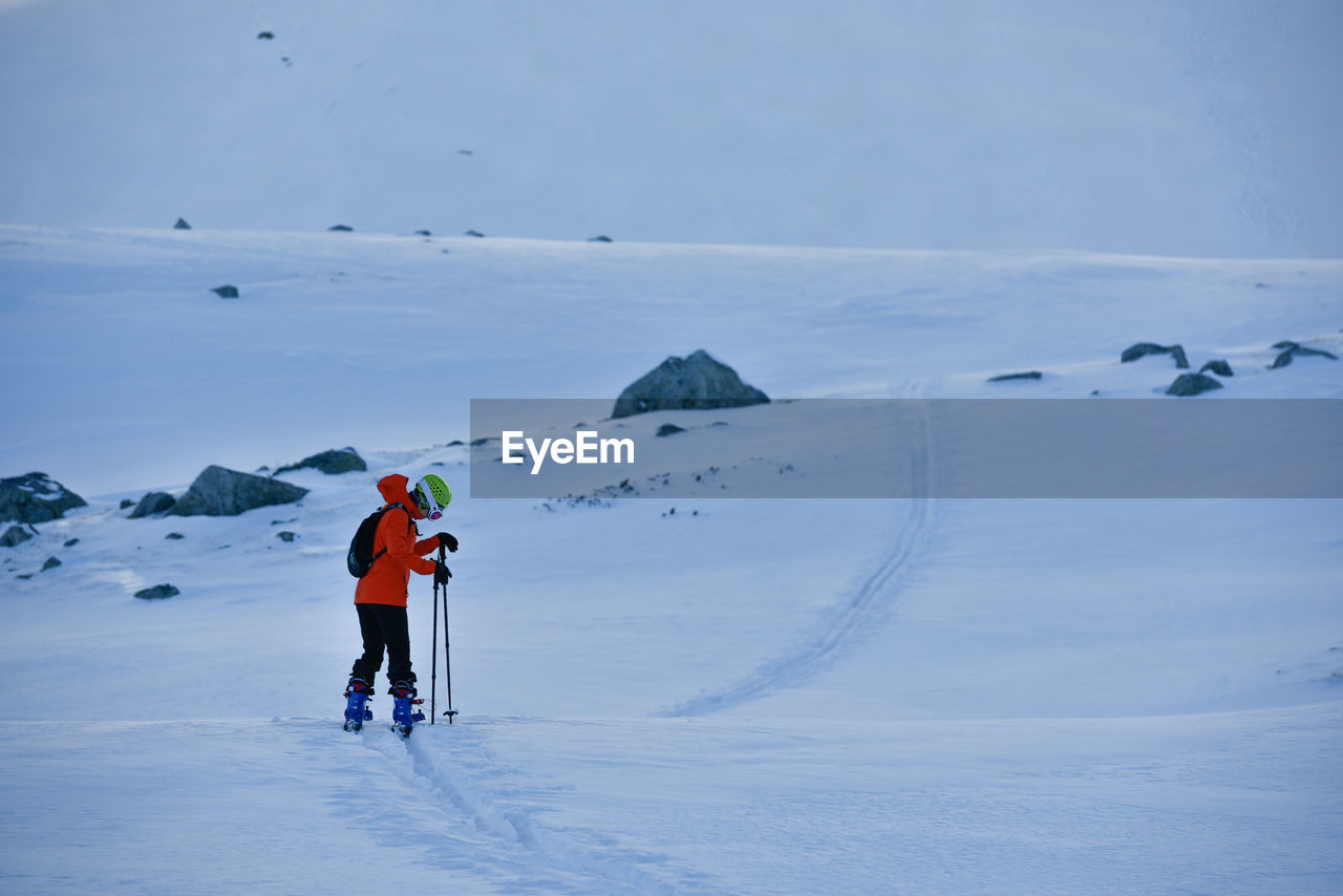 Rear view of person skiing on snow covered landscape against sky