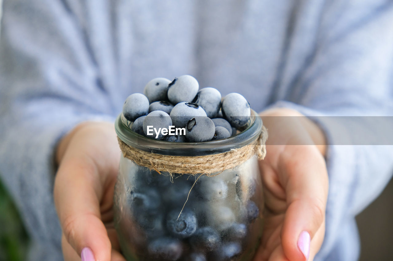 Woman holding bowl with frozen blueberry fruits. harvesting concept. female hands collecting berries