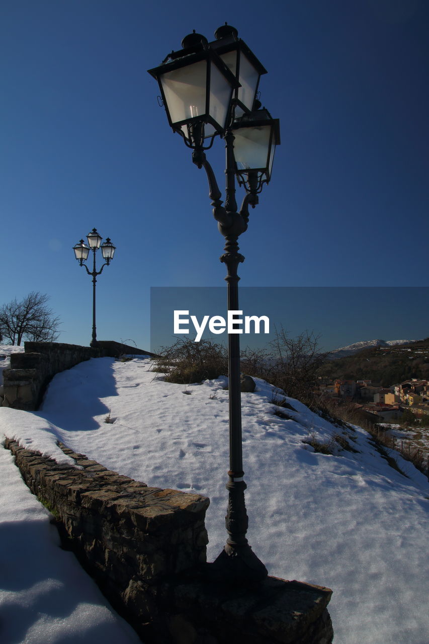 Snow covered street light against clear blue sky