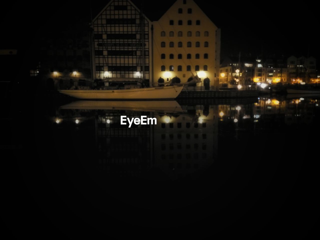 EXTERIOR OF ILLUMINATED BUILDINGS BY RIVER AT NIGHT