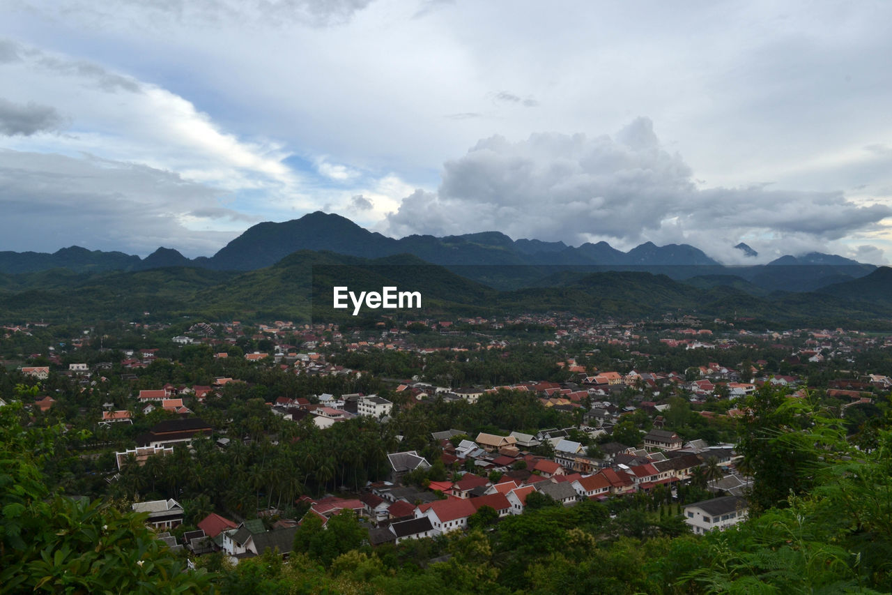 Aerial view of townscape by mountains against sky