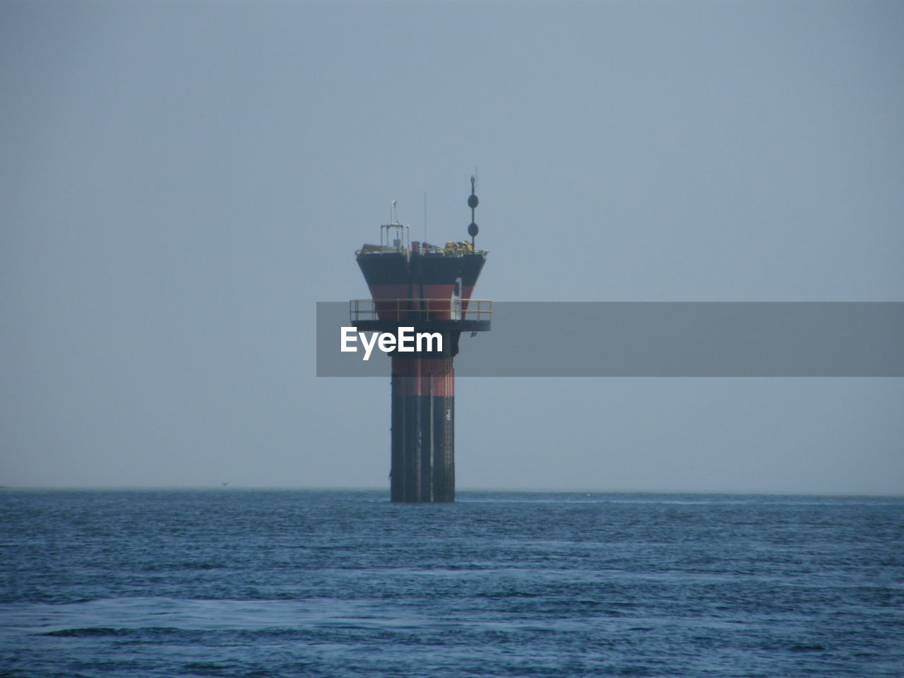 Lighthouse by sea against clear sky