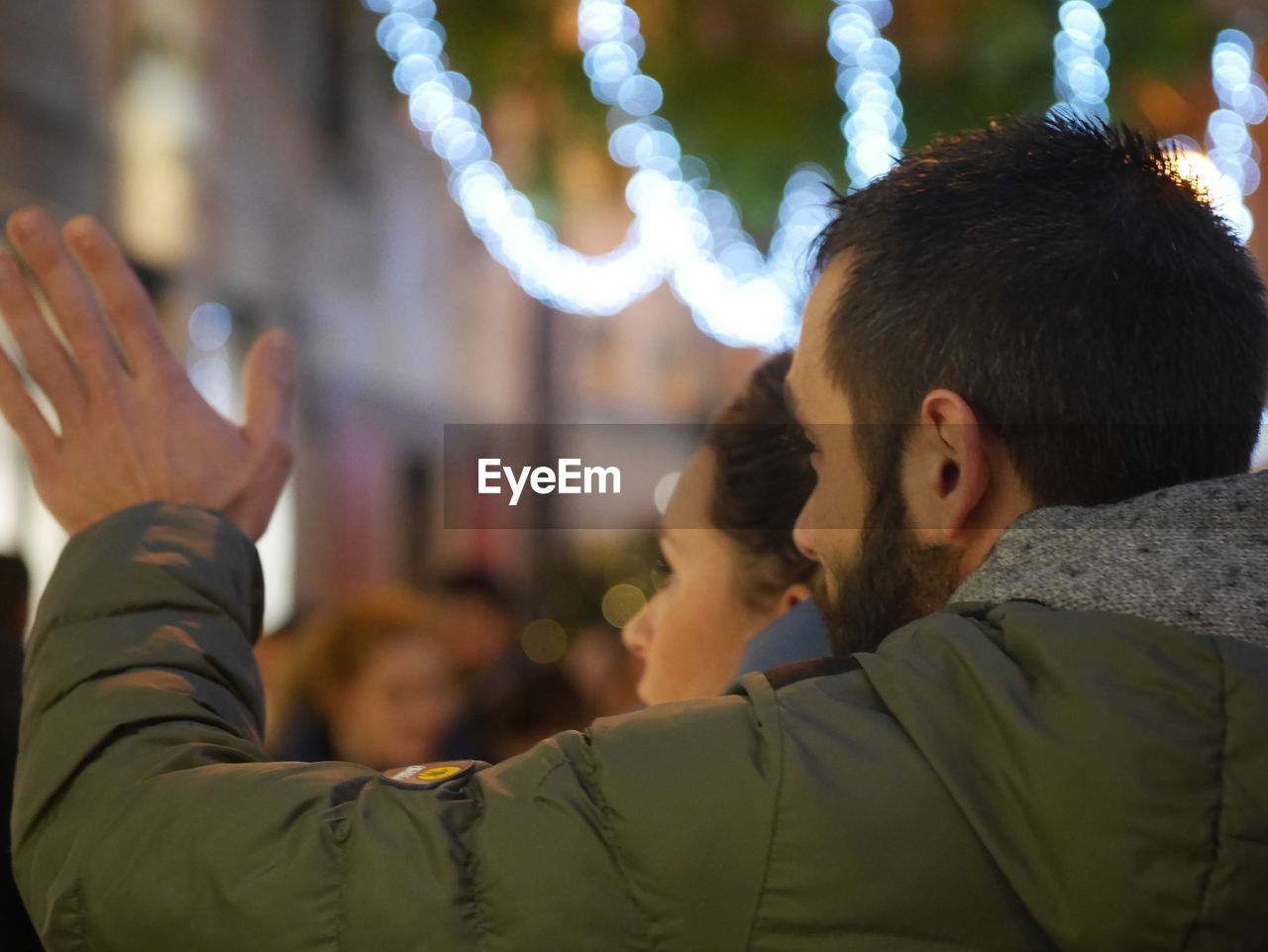 Man gesturing by woman against illuminated lighting equipment at night