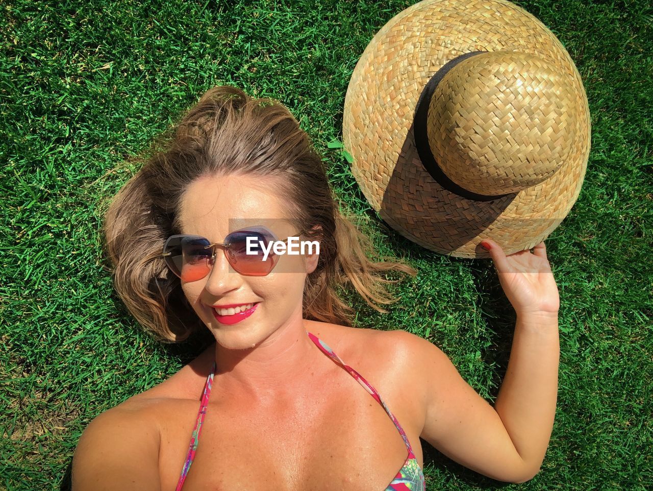 Portrait of happy young woman lying down on the green grass