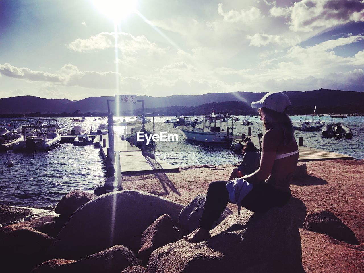 PEOPLE SITTING ON SHORE AGAINST SKY