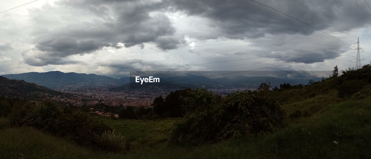 SCENIC VIEW OF TREE MOUNTAINS AGAINST STORM CLOUDS