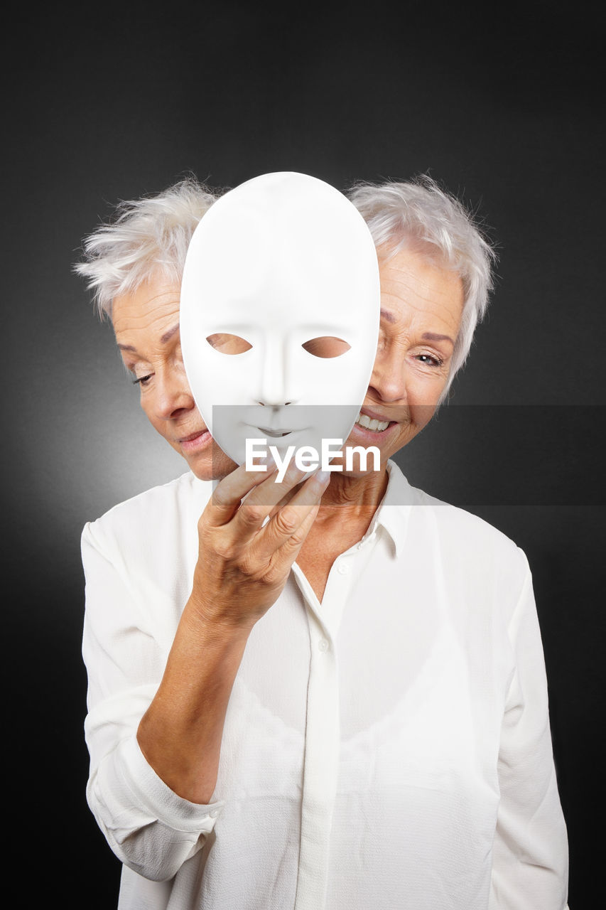 Multiple image of woman holding white mask suffering from schizophrenia against black background