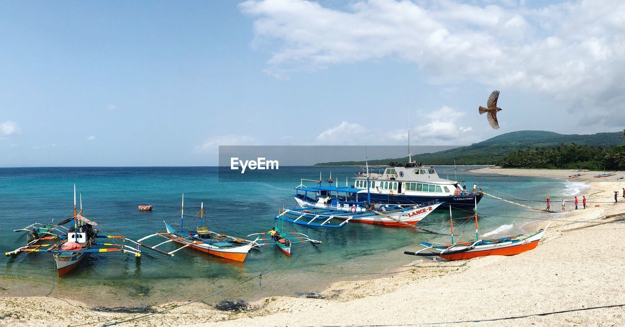 PANORAMIC VIEW OF BOATS MOORED AT SEA AGAINST SKY