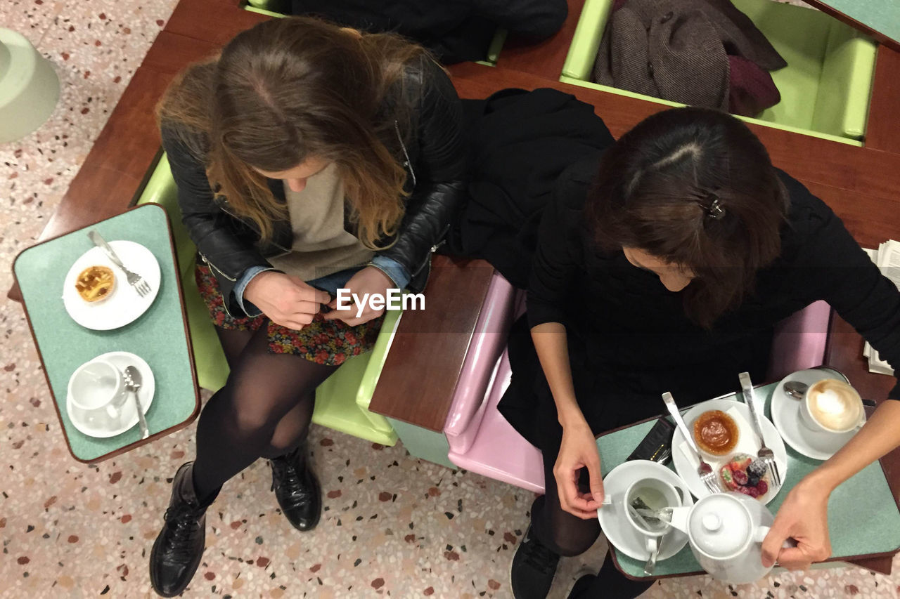 Directly above shot young female friends having coffee in restaurant