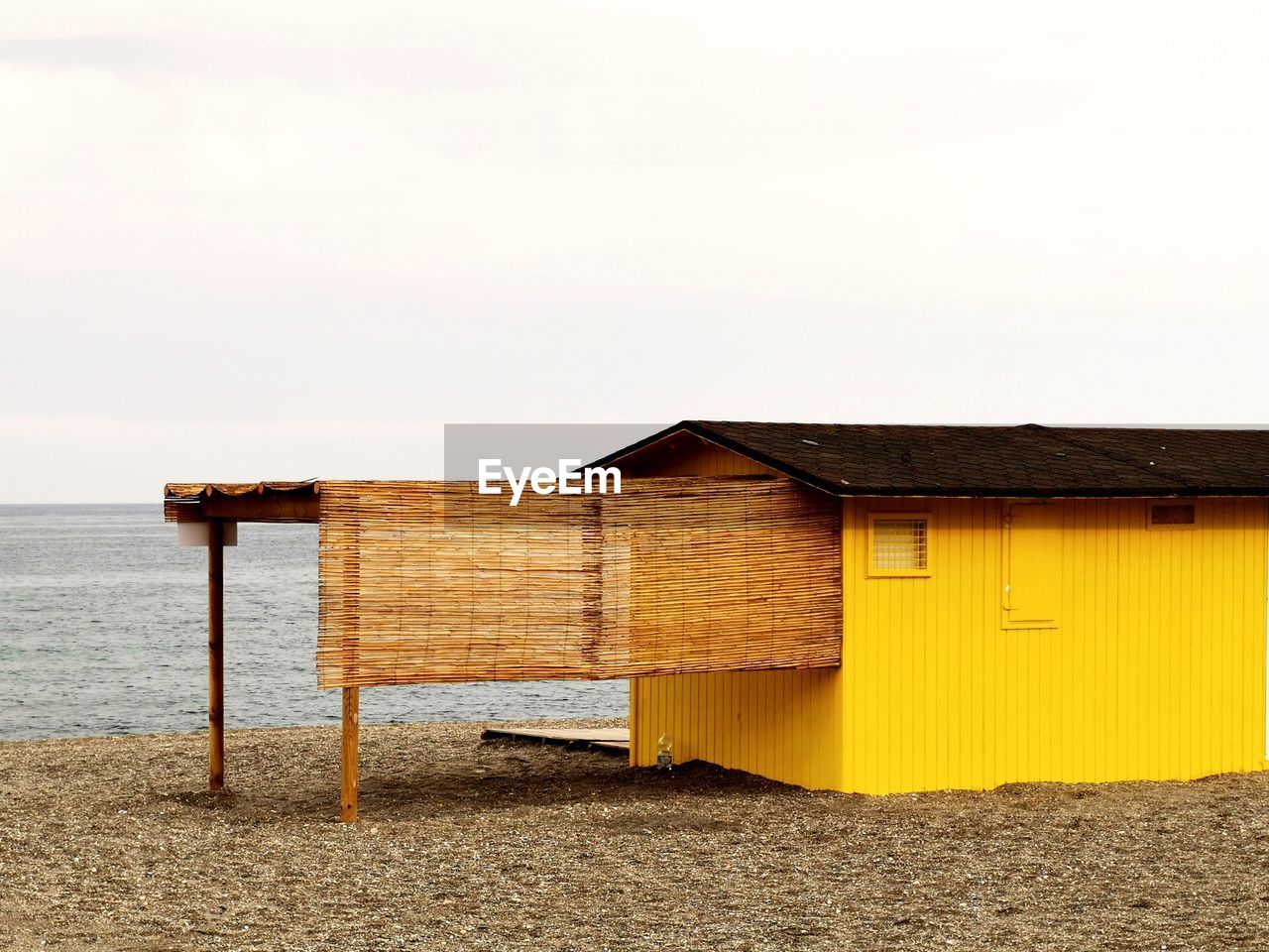 Built structure on beach by sea against clear sky
