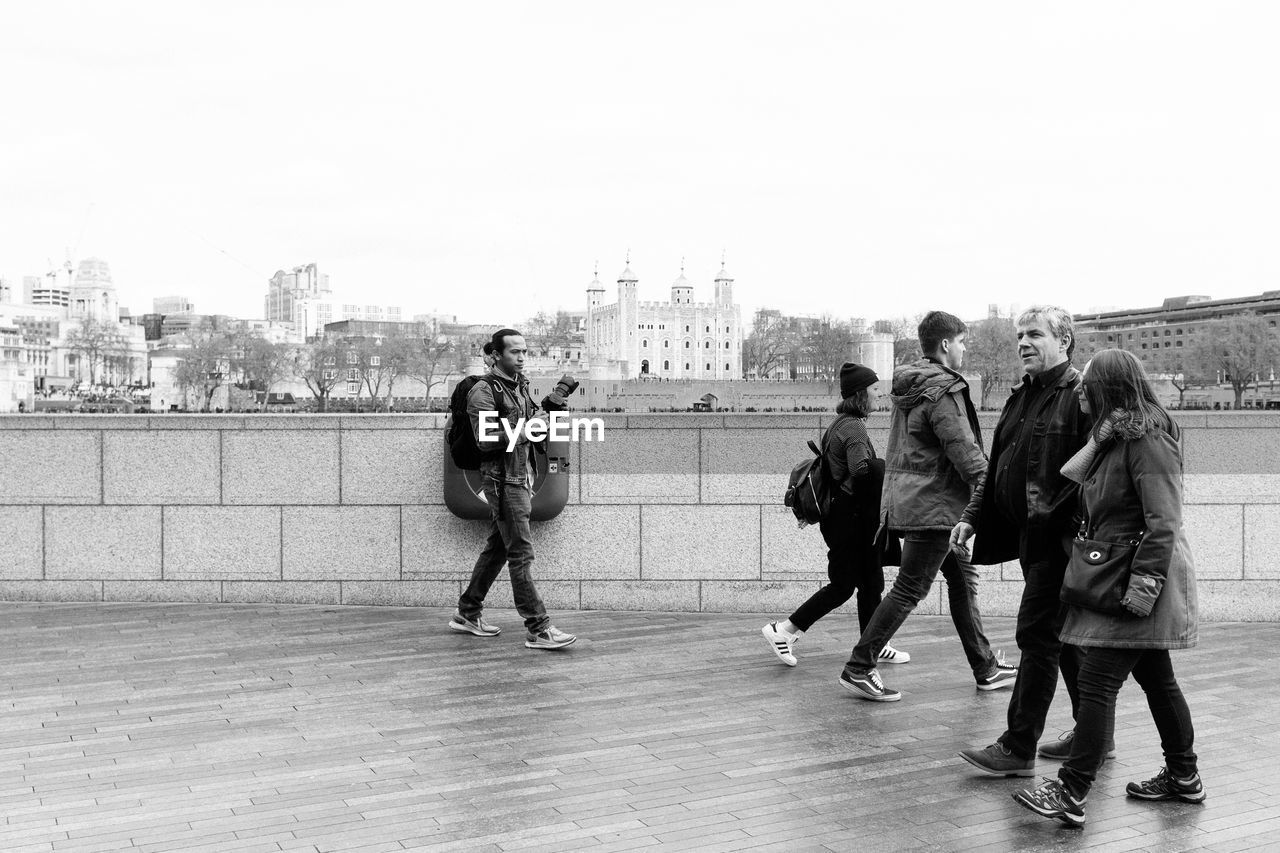 People walking on boardwalk against clear sky