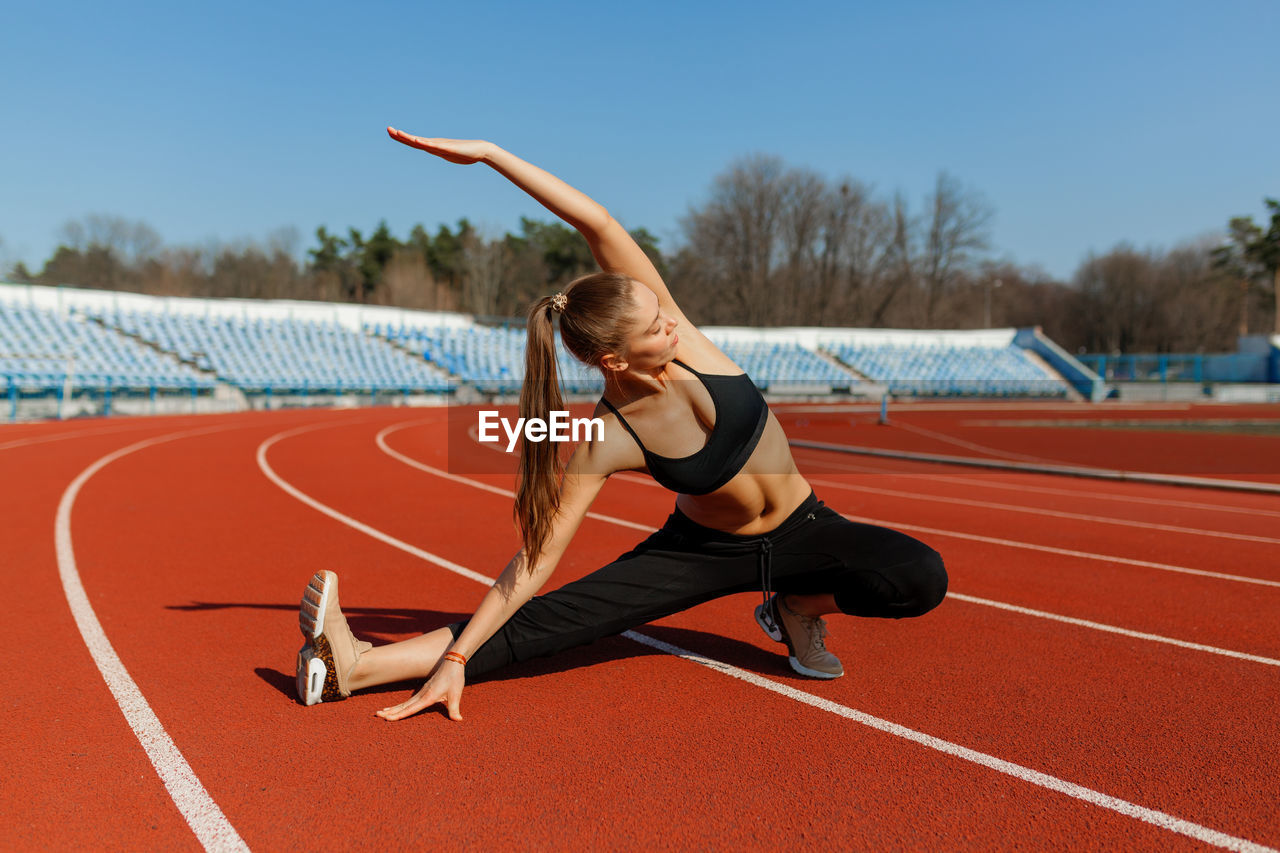 Full length of woman exercising on stadium