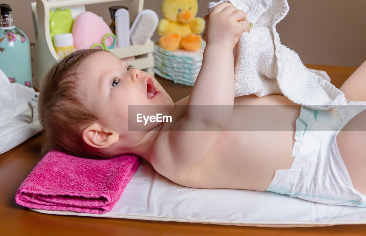 Cute baby girl holding napkin while lying down at home