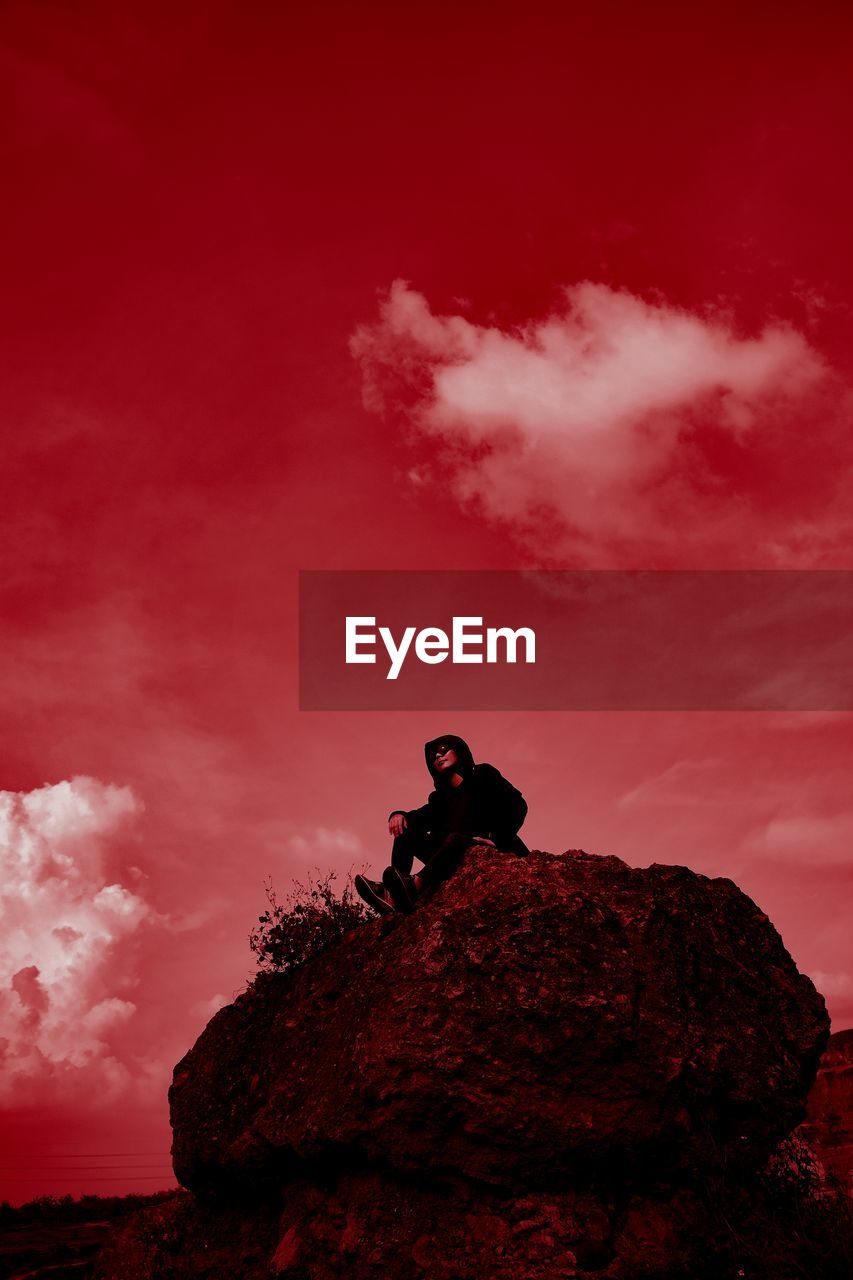 SILHOUETTE MAN STANDING ON ROCK AGAINST RED ROCKS