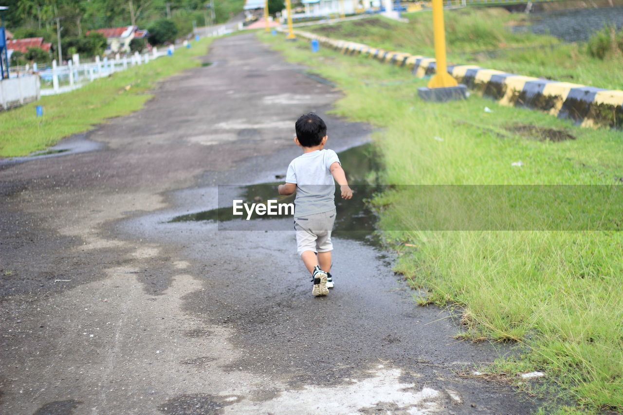 Rear view of boy running on grass