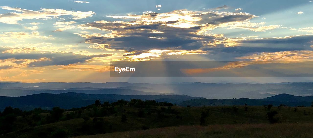 Sunlight streaming through clouds over landscape