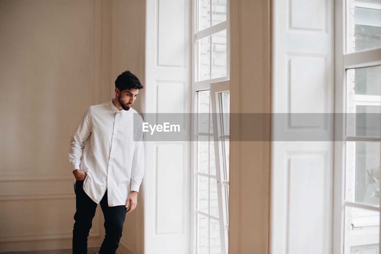 Groom standing by window at home