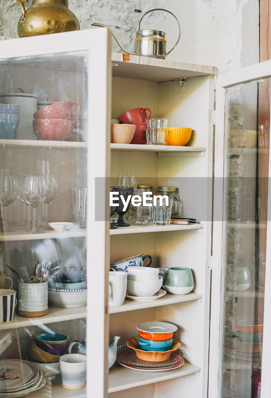 Different ceramic dishes in old wooden vintage sideboard with transparent doors