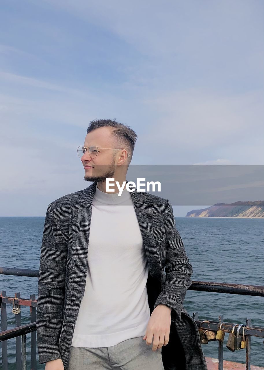 MID ADULT MAN STANDING AGAINST SEA