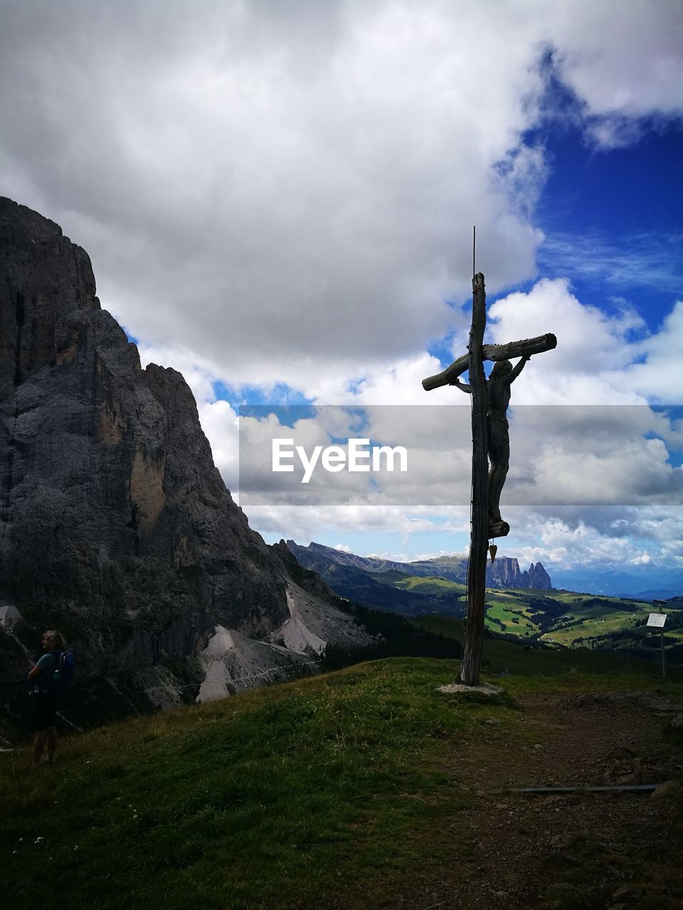 CROSS ON LAND AGAINST CLOUDY SKY