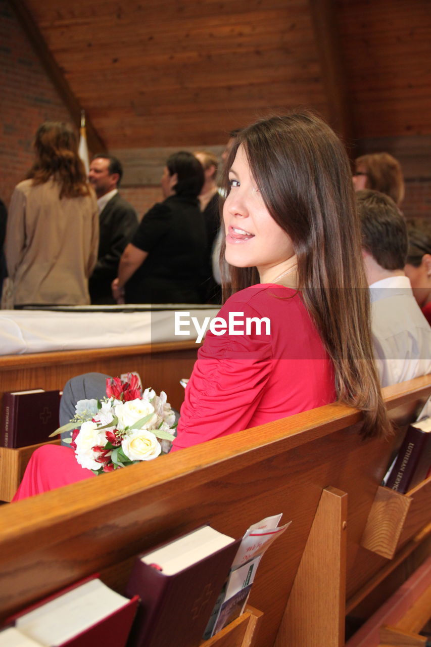 Portrait of young woman sticking out tongue while sitting in church