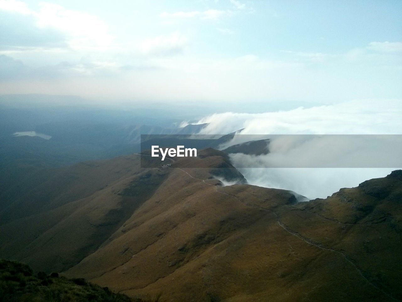 Scenic view of rocky mountains by cloudscape against sky