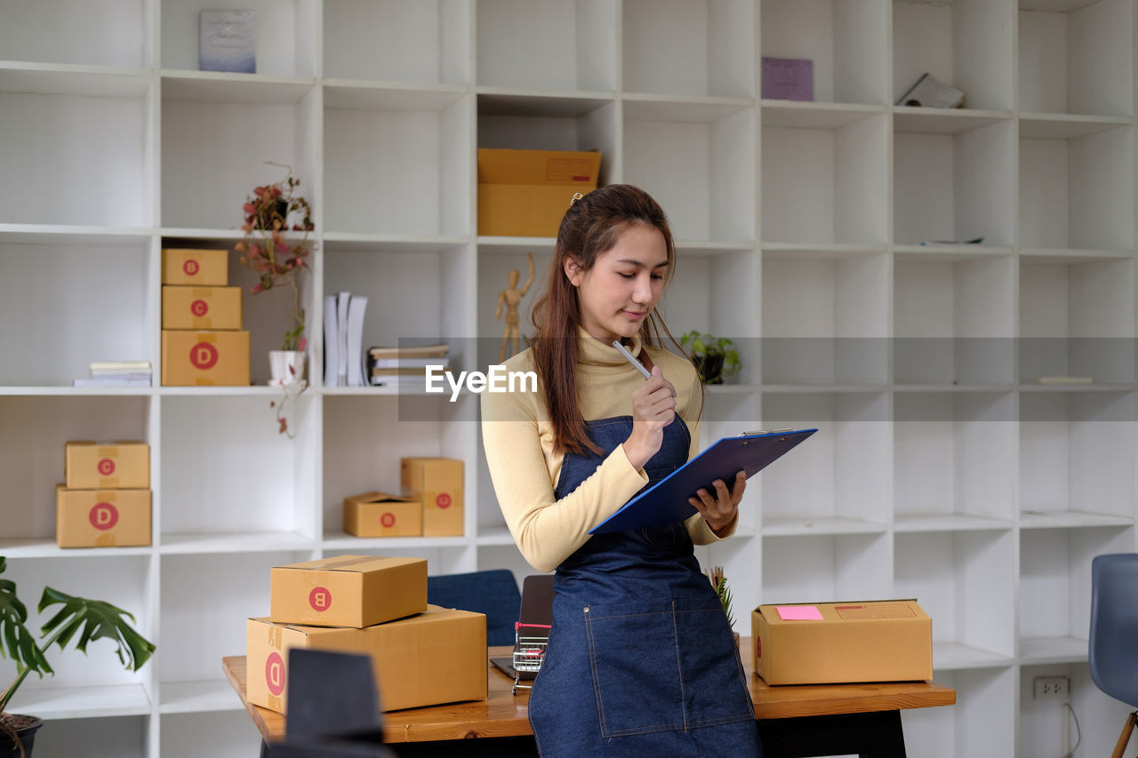 side view of young woman using mobile phone while standing in library