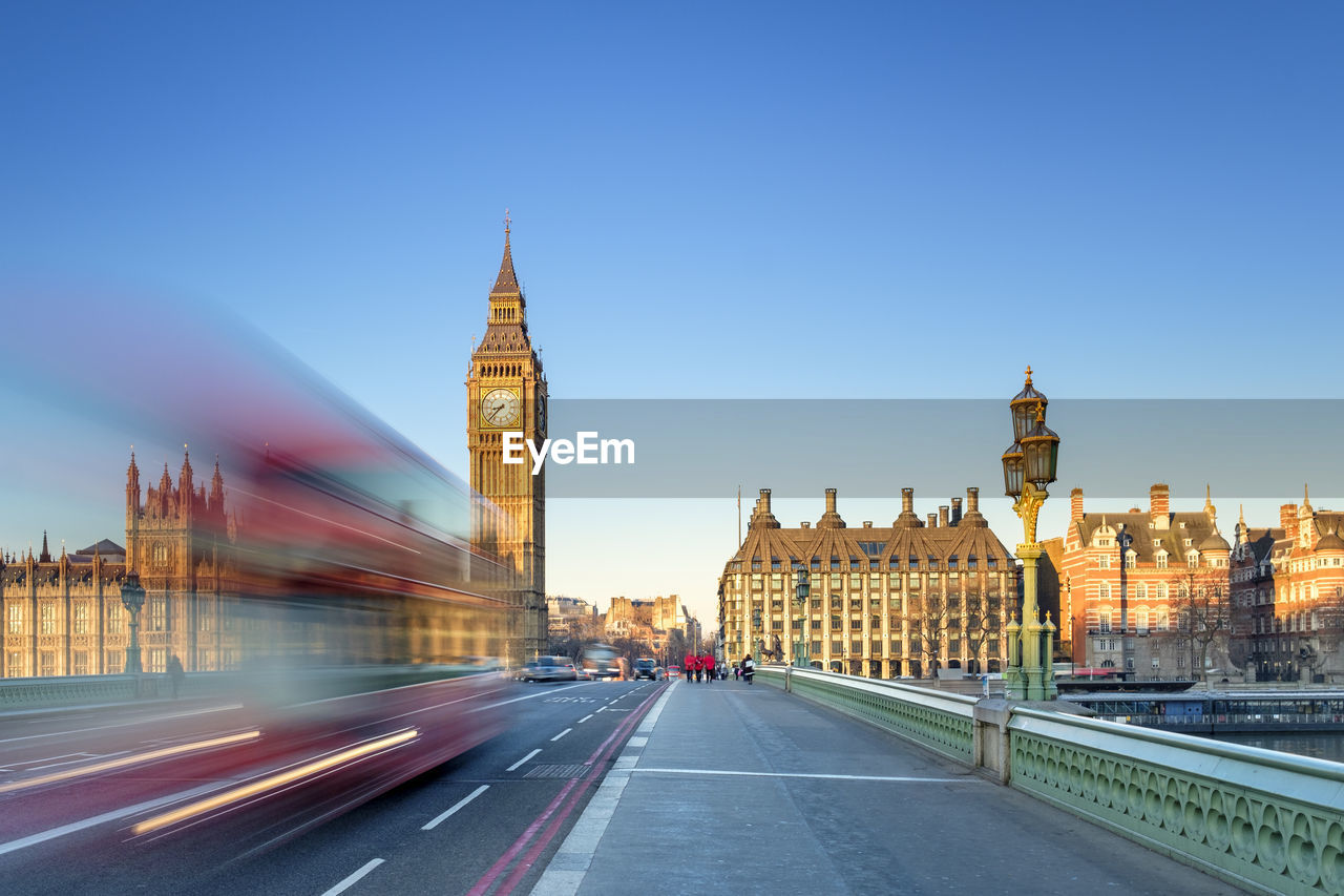 Double-decker bus passes on westminster bridge, in front of westminster palace and clock tower of big ben (elizabeth tower), london, england, united kingdom