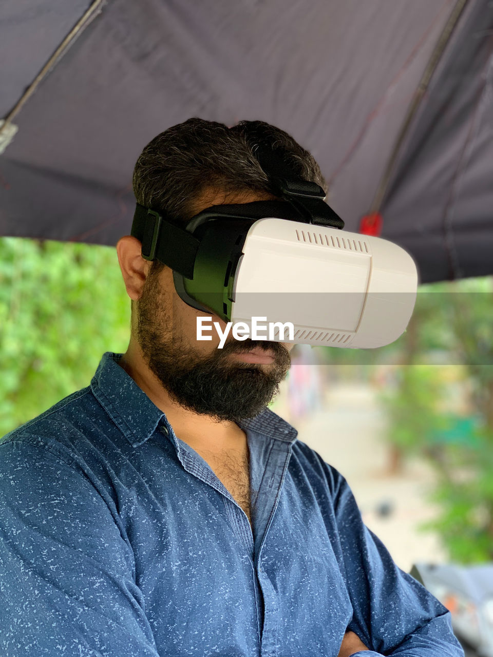 Close-up of man using virtual reality simulator while standing below parasol