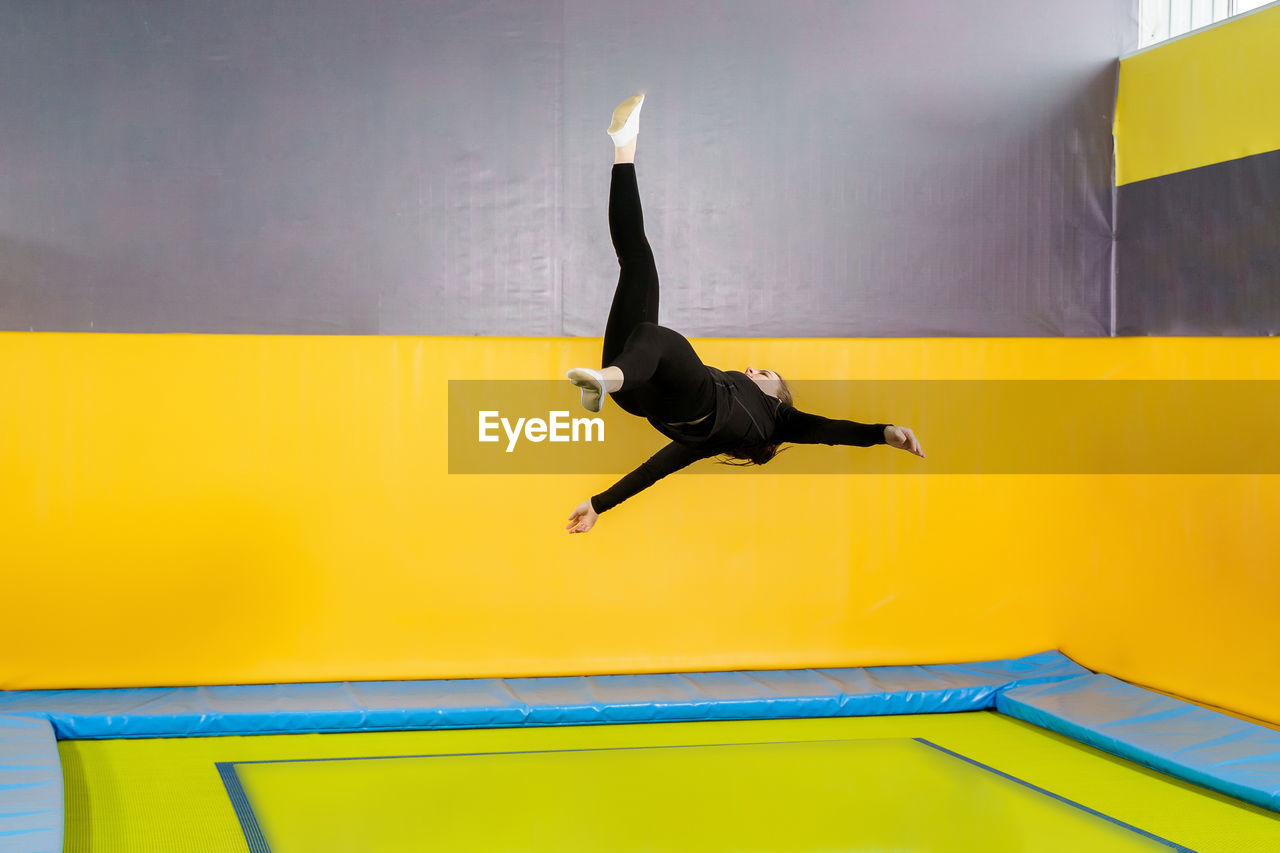 Full length of man jumping against wall