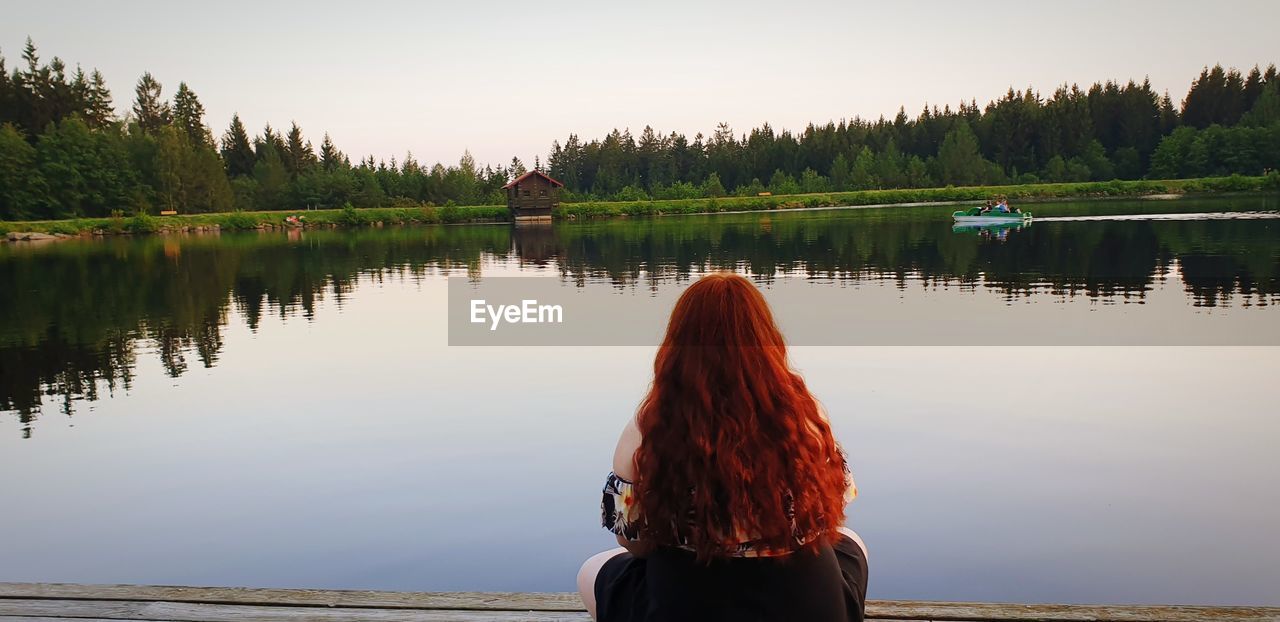 Rear view of woman looking at lake against sky