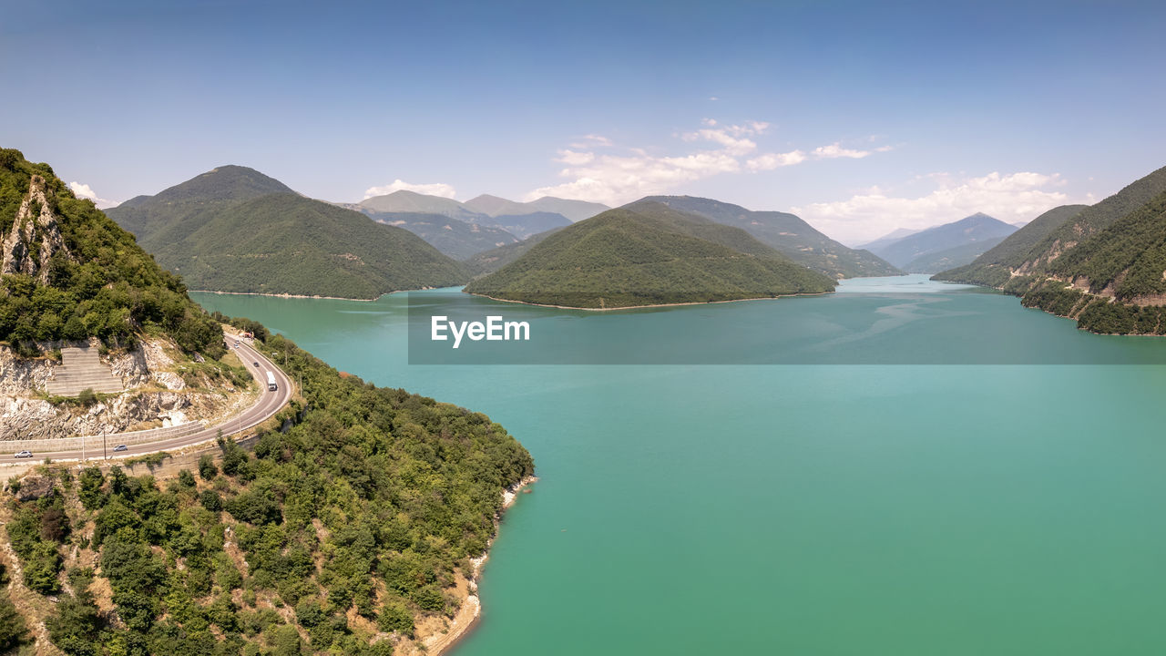 water, mountain, scenics - nature, environment, landscape, beauty in nature, nature, land, sky, lake, mountain range, travel destinations, travel, tranquility, no people, tranquil scene, reservoir, blue, tree, forest, crater lake, tourism, plant, outdoors, panoramic, non-urban scene, environmental conservation, cloud, beach, idyllic, day, green, body of water, summer, architecture, aerial view, vacation, sunny, trip, turquoise colored, holiday, high angle view