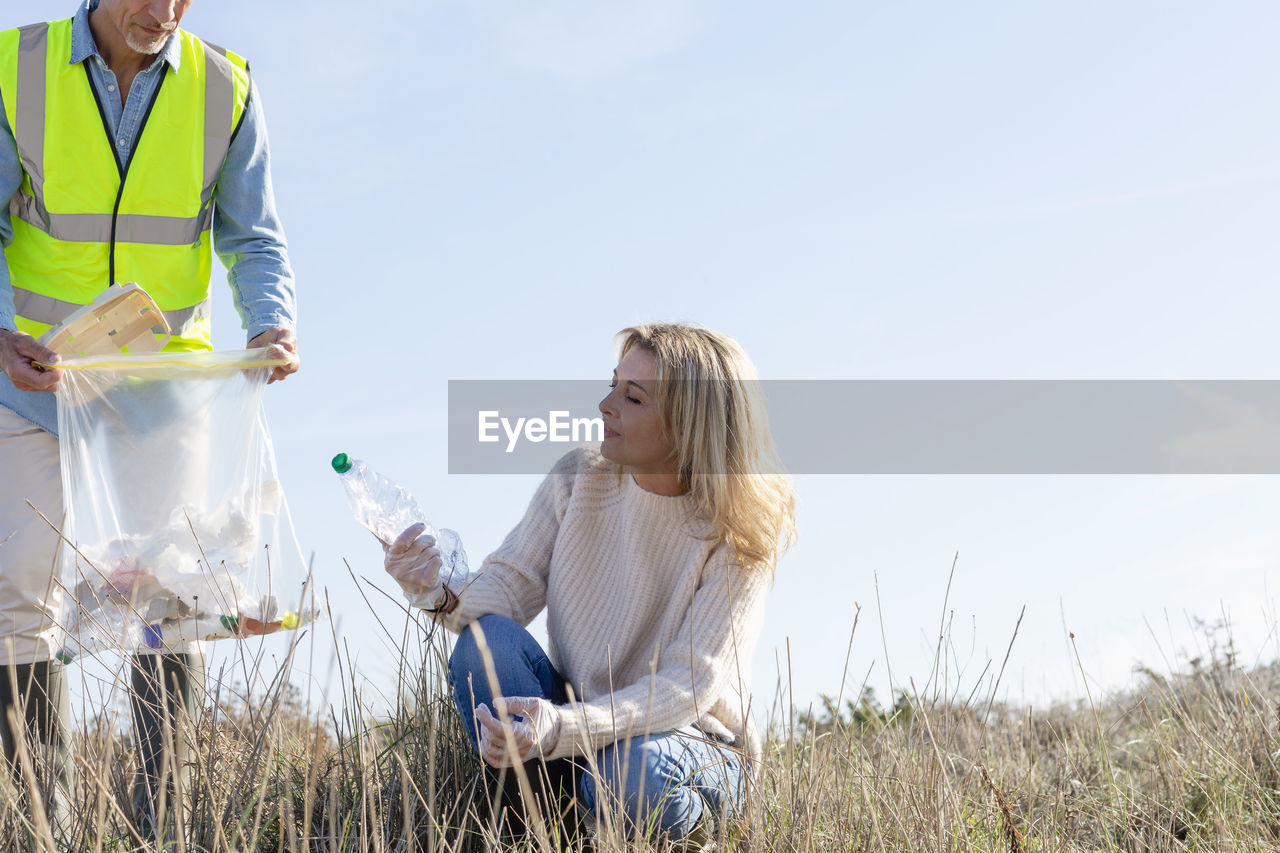 Woman looking at plastic bottle crouching by man