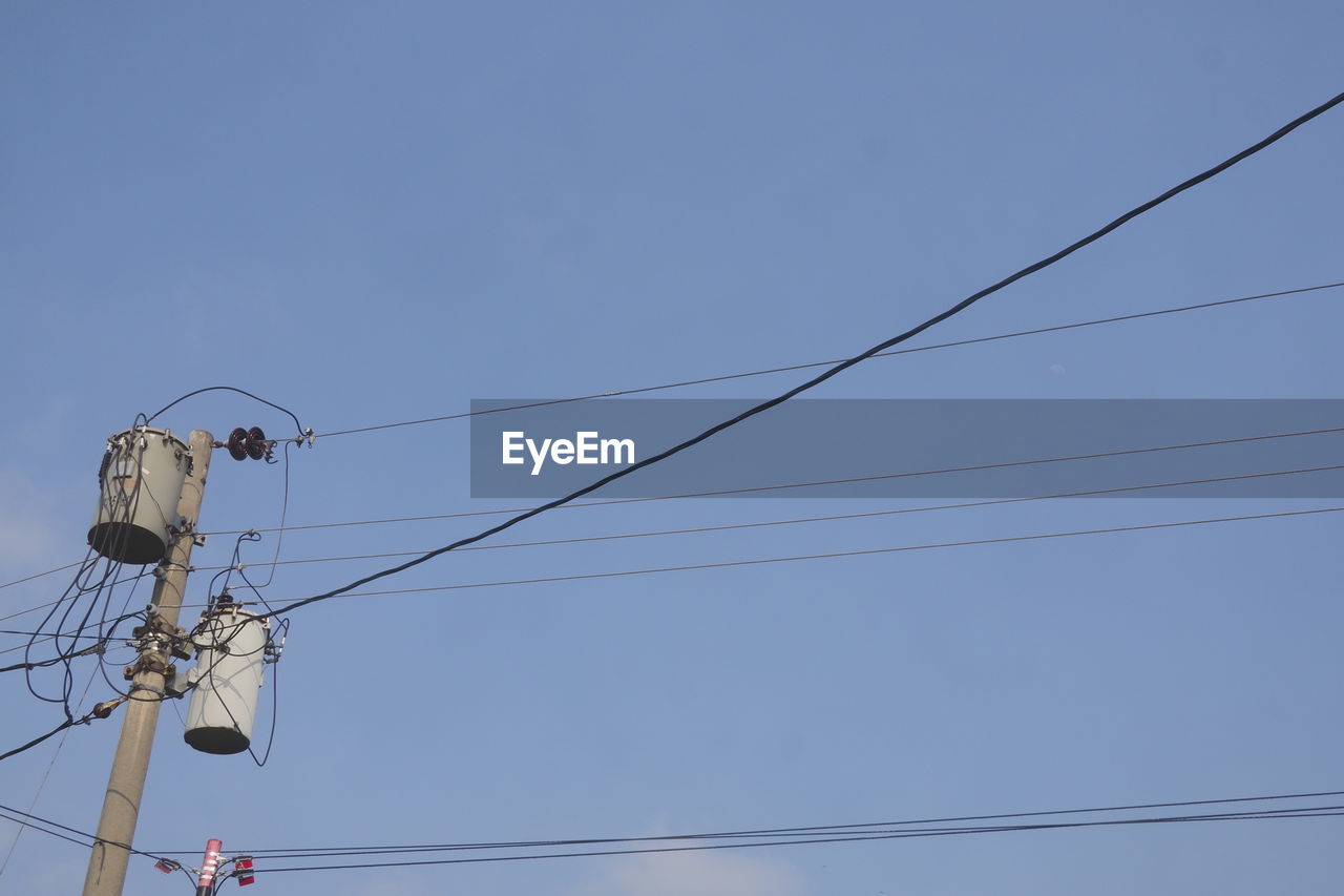 cable, electricity, technology, sky, power supply, power line, overhead power line, low angle view, lighting, power generation, line, blue, electrical supply, electricity pylon, communication, clear sky, telephone line, mast, no people, nature, light fixture, street light, day, outdoors, antenna, copy space, telephone pole, outdoor structure, telephone, computer network, complexity, telecommunications equipment, internet, hanging