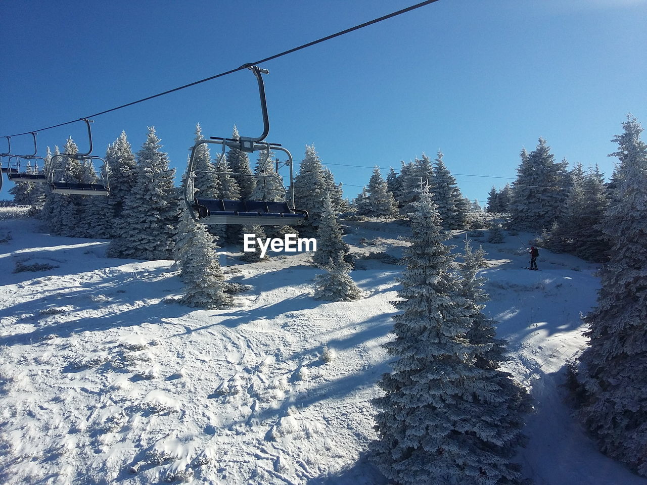 Ski lift over snow covered field against sky