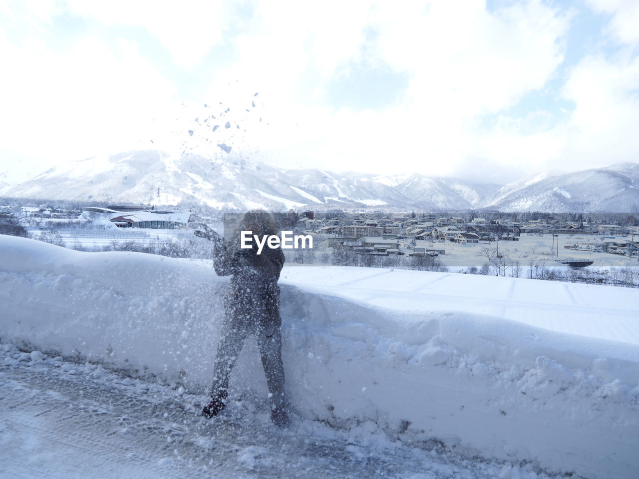 MAN STANDING ON SNOWCAPPED MOUNTAINS AGAINST SKY