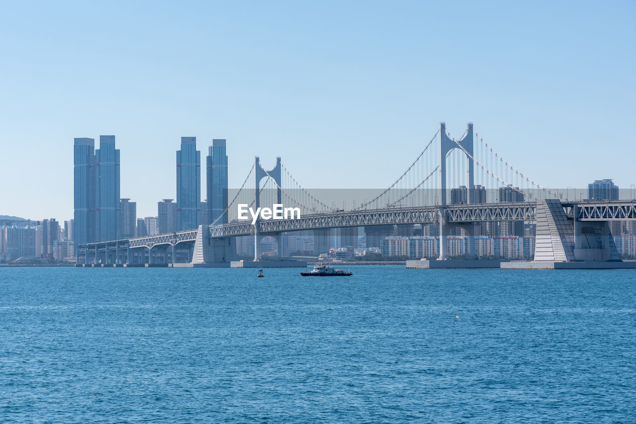 view of suspension bridge in city against clear sky