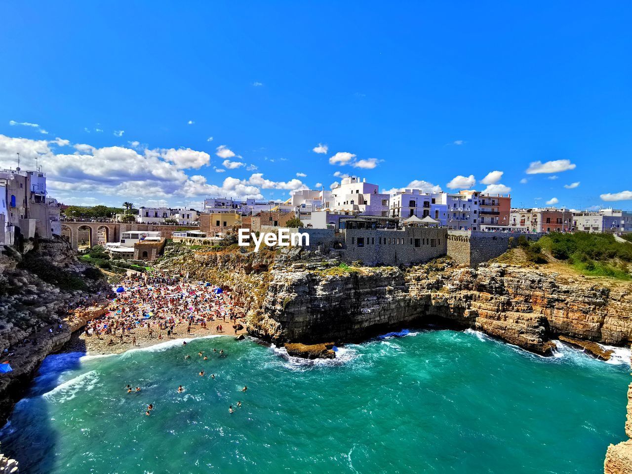 HIGH ANGLE VIEW OF BUILDINGS AND SEA AGAINST CLOUDY SKY