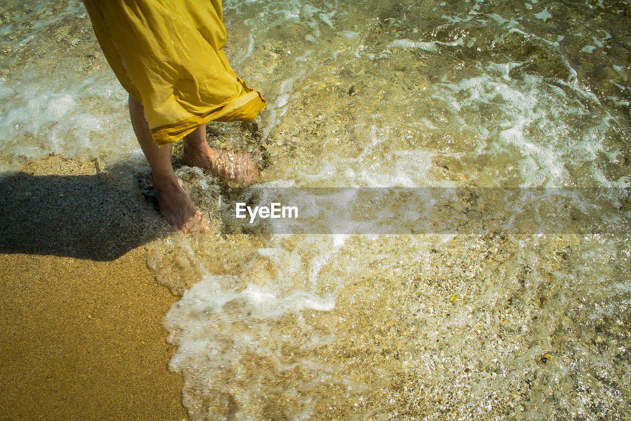 Low section of woman standing at shore