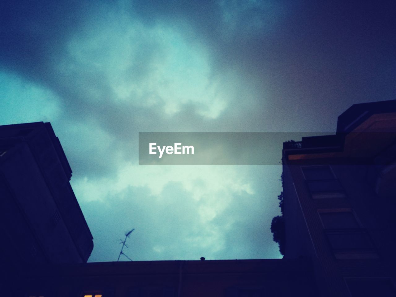 LOW ANGLE VIEW OF BUILDING AGAINST STORM CLOUDS